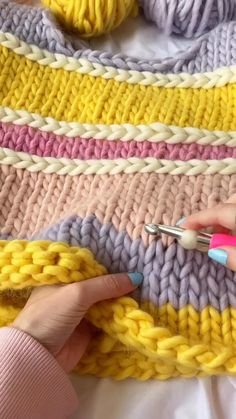 a woman is crocheting the ends of a blanket with scissors and knitting needles