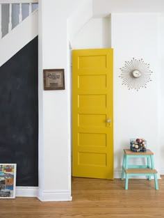 a yellow door is in the corner of a room with white walls and wooden floors