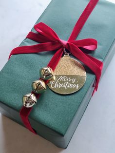 a christmas present wrapped in green paper and red ribbon with a gold ornament