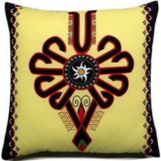 a yellow pillow with black and red designs on it