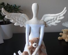 a teddy bear sitting on top of a table next to an angel figurine