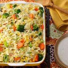 a casserole dish with noodles, carrots and broccoli