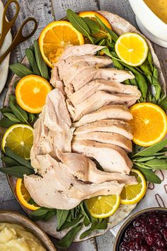 sliced turkey on a platter with oranges and cranberry sauce