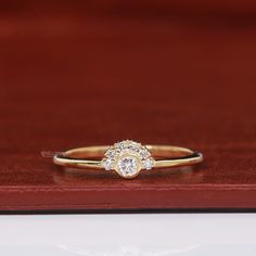 a diamond ring sitting on top of a wooden table next to a red velvet box