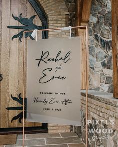 a sign that says rachel and eric welcomes guests to their wedding ceremony in front of a stone building