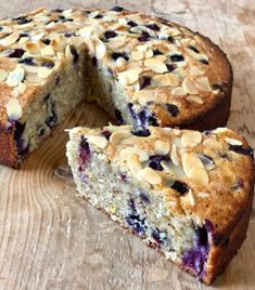 a cake with blueberries and almonds cut in half on a wooden table top