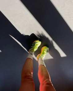 the shadow of a person's feet and tennis shoes on a tennis court floor