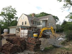 a house being built with bricks stacked on the ground and a bulldozer in front