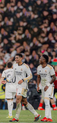 two soccer players are walking together on the field in front of an audience at a sporting event