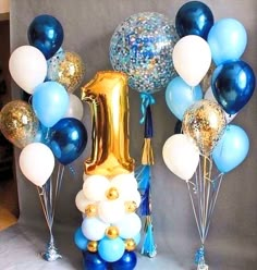 blue and white balloons are in front of a balloon arch with the number one on it