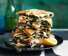 a stack of quesadillas stacked on top of each other with lemon wedges