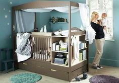 a woman standing next to a baby crib in a room with blue walls and carpet