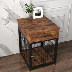 a small wooden table with a metal cage on the bottom and a potted plant on top