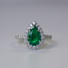 an emerald and diamond ring on a white surface