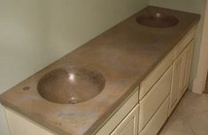 a bathroom counter top with two sinks and cabinets in it, next to a door