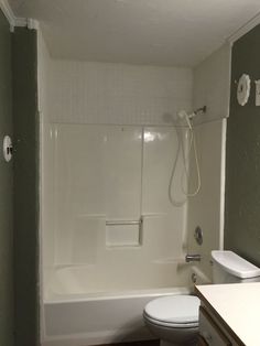 a white toilet sitting next to a bath tub