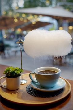 a cup of coffee sitting on top of a wooden table next to a white cloud