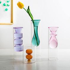 three vases with flowers in them sitting on a table next to each other,