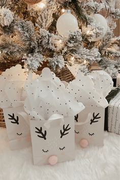 small gift bags decorated with black and white deer faces are sitting in front of a christmas tree