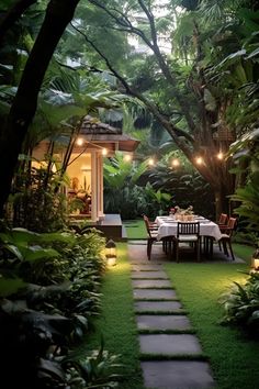 a table and chairs in the middle of a lush green yard with lights on it