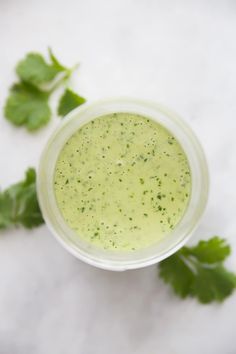 a small cup filled with green liquid and garnished with cilantro leaves