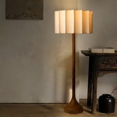 a lamp that is next to a table with a book on it and a vase