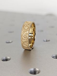 a gold wedding ring sitting on top of a metal surface