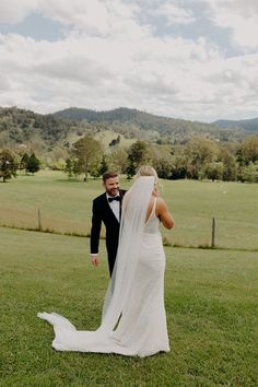 a bride and groom walking in the grass