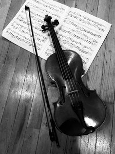 an old violin sits on the floor next to music sheets