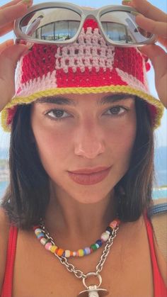 a woman wearing sunglasses and a hat with beads on it's brim is looking at the camera