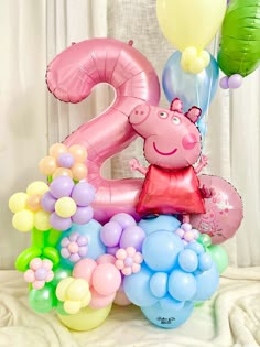 a number two balloon arrangement with balloons in the shape of peppa pig and an elephant