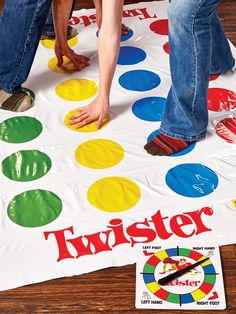 two people standing on top of a giant white board game with colorful circles and letters