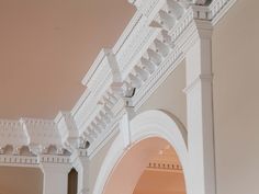 the inside of a building with white columns and arches on each side, along with an arched doorway