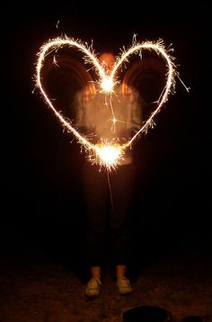 a person holding a sparkler in the shape of a heart