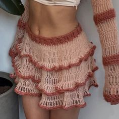 a woman is wearing a skirt with crochet on it and has her hands behind her back