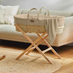 a baby's bassinet is sitting on the floor in front of a couch