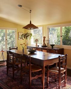 a dining room table with four chairs and a potted plant in the center on top of it