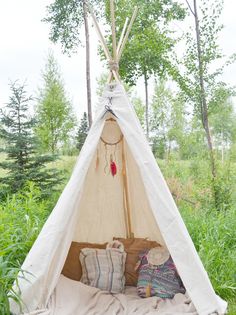 a teepee tent in the woods with pillows