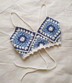 two crocheted blue and white squares are on a bed with the string down