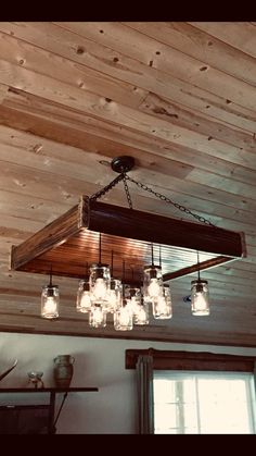 a chandelier with mason jar lights hanging from it's wooden ceiling fixture