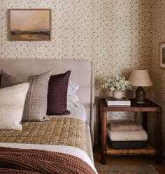 a bed sitting next to a night stand on top of a wooden table in a bedroom