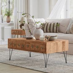 a living room with a couch, coffee table and vases on the end tables