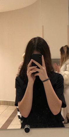 a woman taking a selfie in front of a bathroom mirror with her cell phone