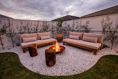 a fire pit in the middle of a backyard with couches and tables around it