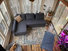 a living room with a sectional couch and rug in the middle, looking down on it