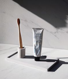 a tube of toothpaste next to a toothbrush on a white tray with marble background