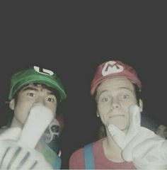 two young men dressed up in mario and luigi hats, one holding his hand to his face