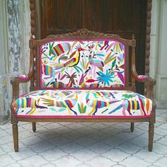 a colorfully decorated couch sitting in front of a wooden door on a tiled floor