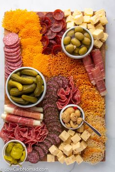 an assortment of meats and cheeses on a platter with pickles, olives, bread