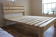 a bed frame made out of wood in a room with hardwood floors and white walls